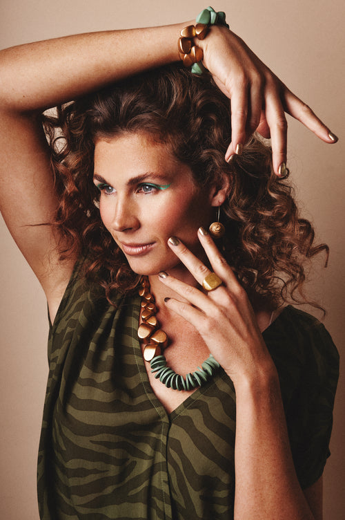 Model wears Bananas wooden necklace Liron in sage green and gold, wooden bracelet Liron in sage green and gold. Combined with silver ring from Rima Jewelry 925 silver gold plated